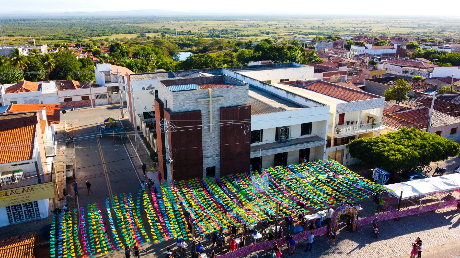 Vista aérea da Igreja de Santo Antônio com bandeirinhas e a comunidade reunida em frente à matriz